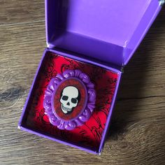 a purple box with a skull on the front and inside, sitting on a wooden table