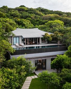 an aerial view of a house in the middle of some trees and grass with stairs leading up to it