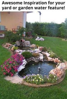 a small pond in the middle of a lawn with flowers and rocks around it, next to a house