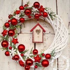 a wreath with ornaments and a birdhouse hanging on the front door to decorate for christmas