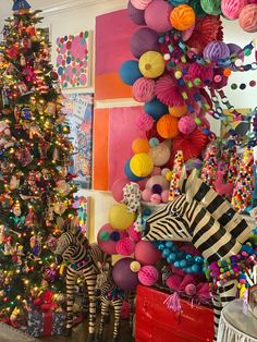 there is a christmas tree decorated with colorful balls and zebras in front of it