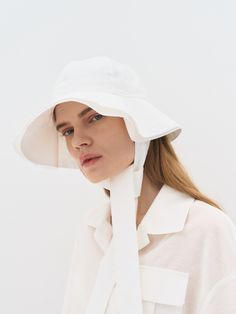 a woman wearing a white hat with a tie around it's brimming