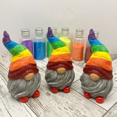 three gnomes made out of clay sitting on top of a wooden table next to bottles