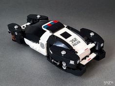 a police car made out of legos sitting on a table next to a black and white wall