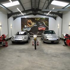 three cars parked in a garage next to motorcycles