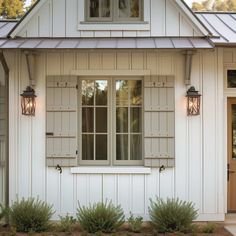 a white house with two lights on the front door and windows above it's doors