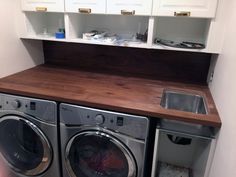 a washer and dryer in a small room with cabinets above the washer