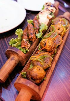 two wooden spoons filled with food on top of a table