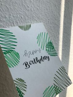 a piece of paper with the words happy birthday written on it and green brush strokes