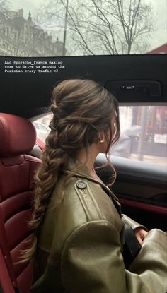 a woman sitting in the back seat of a car with her hair pulled into a braid