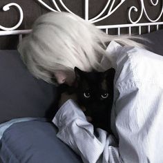 a black cat laying on top of a person in bed