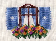 a cross stitched picture of an open window with flowers