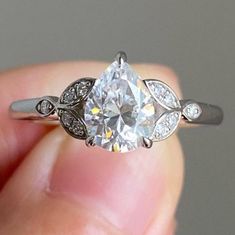 a close up of a person's hand holding an engagement ring