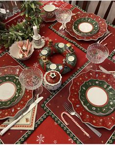 a table set for christmas dinner with plates, silverware and candy canes