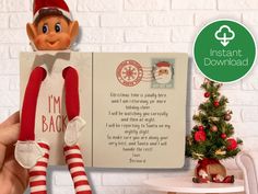 an elf holding up a christmas card with the message i'm back on it