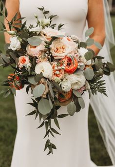 a bride holding a bouquet of flowers and greenery