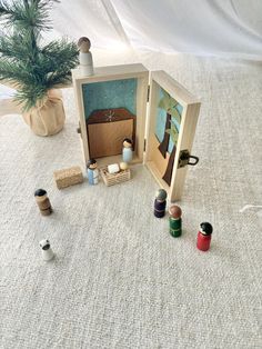 an open wooden box with several different items in it on the floor next to a potted plant