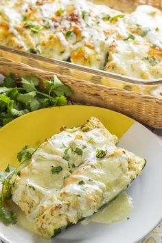 a yellow plate topped with lasagna covered in cheese and herbs next to a casserole dish