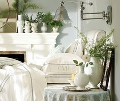 a white bed sitting next to a fireplace covered in pillows and blankets on top of a table