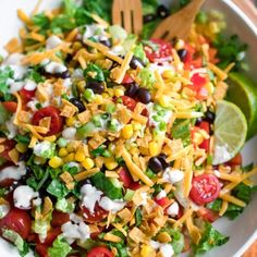 a salad with corn, tomatoes, lettuce and black olives in it