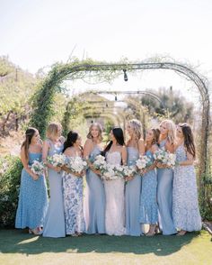 a group of women standing next to each other in front of a pergol arch