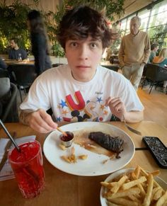 a young man sitting at a table with food in front of him