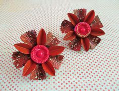 two red flower shaped brooches sitting on top of a polka dot table cloth