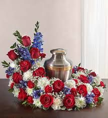 a vase filled with red, white and blue flowers on top of a wooden table