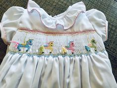 Hand-smocked little girl's dress is made of white Imperial broadcloth with ruffle at the neck with puffy sleeves.  Colorful carousel horses.  It can be made with angel sleeves, or short puff sleeves.  Can  also be made with other colored smocking or fabrics.  Choices: - Peter Pan collar with lace - Pink stitching around the collar - Pink trim and lace around the sleeves - Paster colors for the horses  - Colorful bright colors for the horses - Pink horses If you have any questions please do not h Playful Multicolor Smocked Dress With Ruffles, Playful Fitted Smocked Dress For Playtime, Playful White Smocked Dress, White Playful Smocked Dress, Playful White Dress With Smocked Back, Playful White Smock Dress, Carousel Birthday, Smocking Patterns, Angel Sleeves