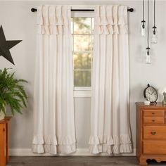 a white curtain with ruffled edges hangs in front of a wooden dresser and window