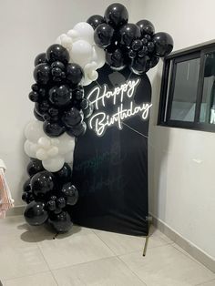 a black and white birthday arch with balloons