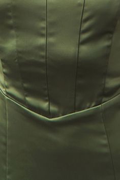 the back of a woman's green dress with pleaing on the bottom and side