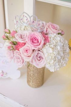 a vase filled with flowers and a tiara on top of a table next to a mirror