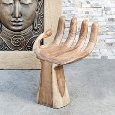 a wooden chair sitting in front of a brick wall next to a buddha head statue