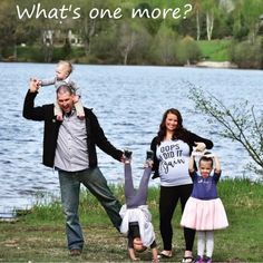 a man, woman and two children are posing in front of a lake with the caption what's one more?