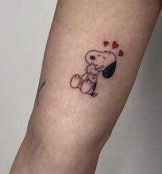 a small tattoo on the leg of a person with a dog and hearts in it