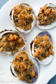 four open oysters with crumb topping on a white plate