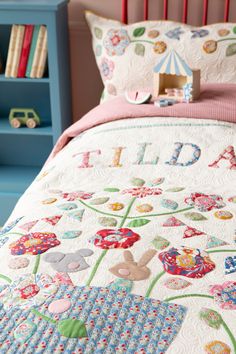 a child's bed with colorful quilts and toys on the headboard next to it