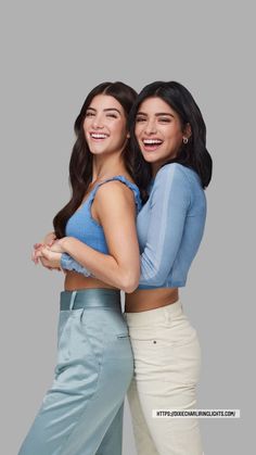 two women standing next to each other with their arms around one another and smiling at the camera