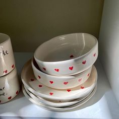 a stack of white dishes with red hearts on them