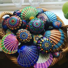 a basket filled with lots of different colored seashells on top of a window sill