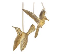 two gold hummingbirds hanging from strings on a white background, one is yellow and the other is brown