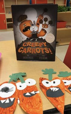 two paper carrots with faces cut out to look like cartoon characters