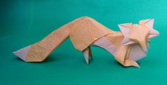 an origami cat laying on its side with it's tail curled up