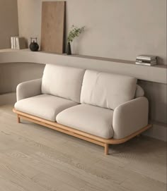 a white couch sitting on top of a hard wood floor next to a shelf filled with books