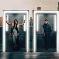 two men standing in front of three mirrors with their hands up and one holding his arms out