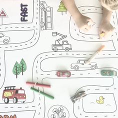 a child is drawing on the paper with markers and crayons in front of them