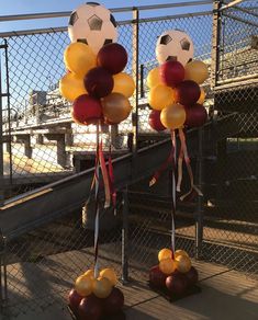 some balls and balloons are hanging on the fence