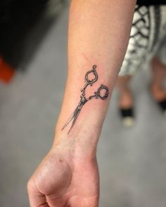 a person with a tattoo on their arm holding a pair of scissors in one hand