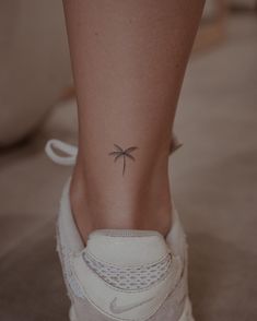 a woman's foot with a small palm tree tattoo on her left side ankle